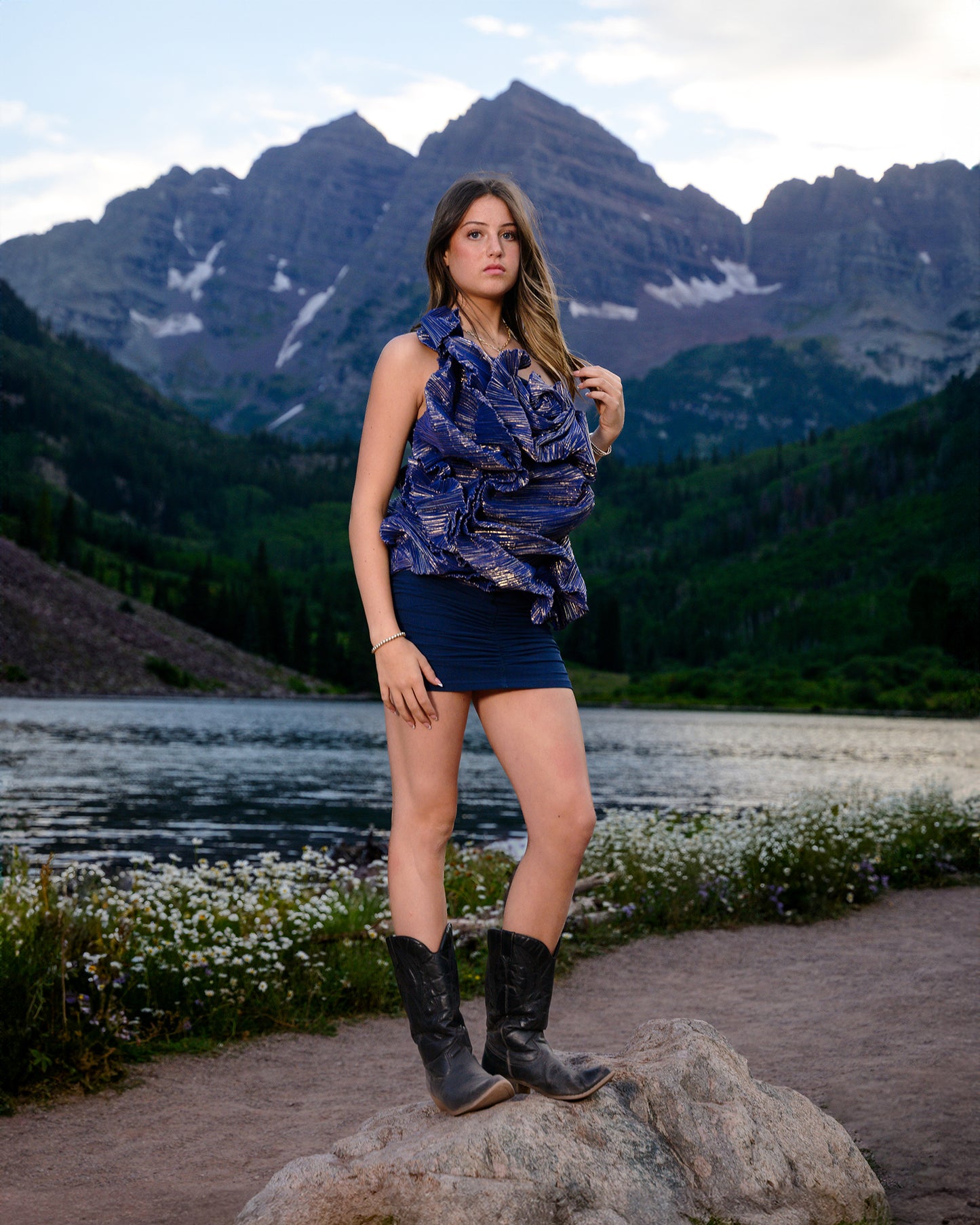 Woman standing on a rock with mountains and a lake in the background