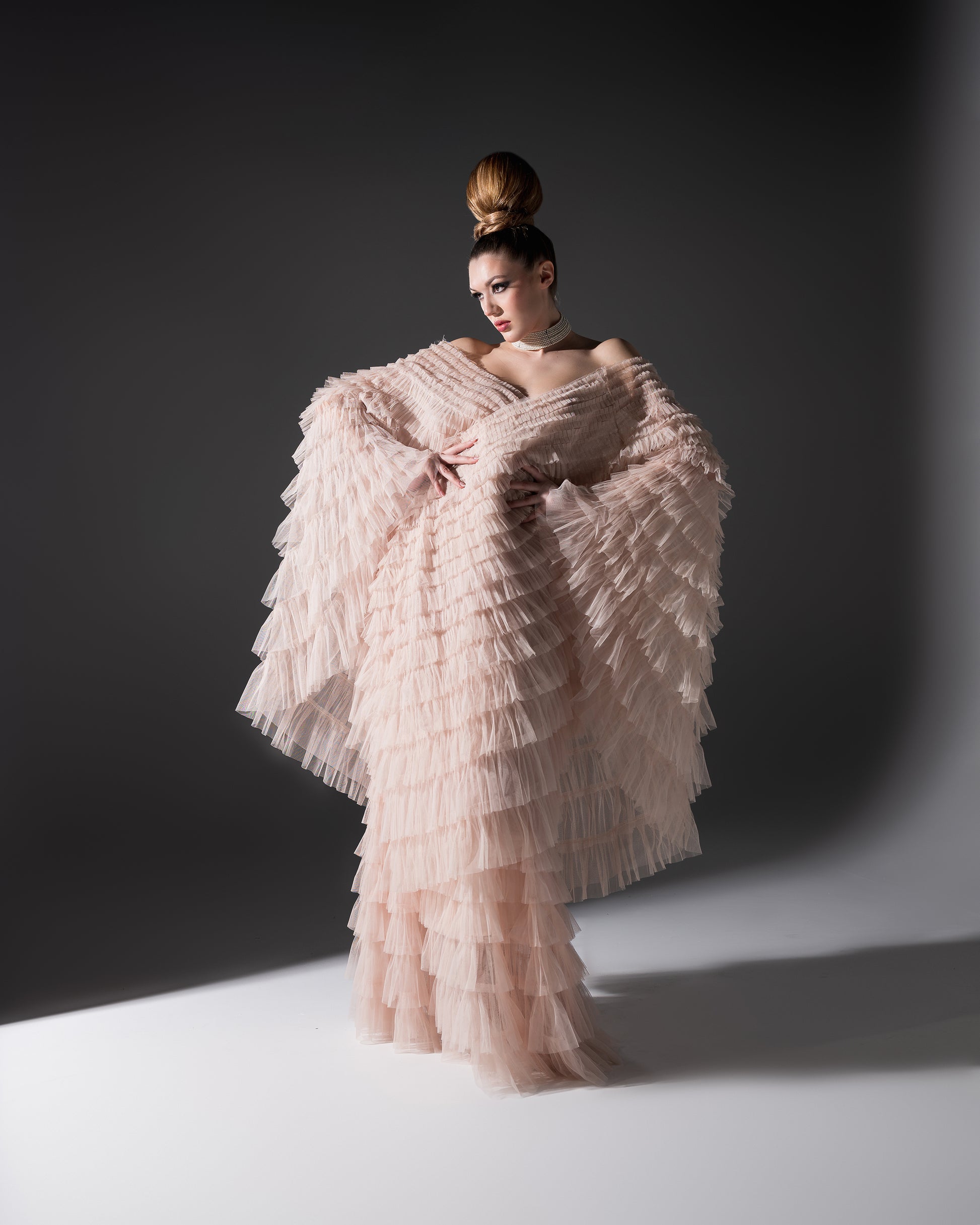 Woman in a pink, ruffled gown against a dark background