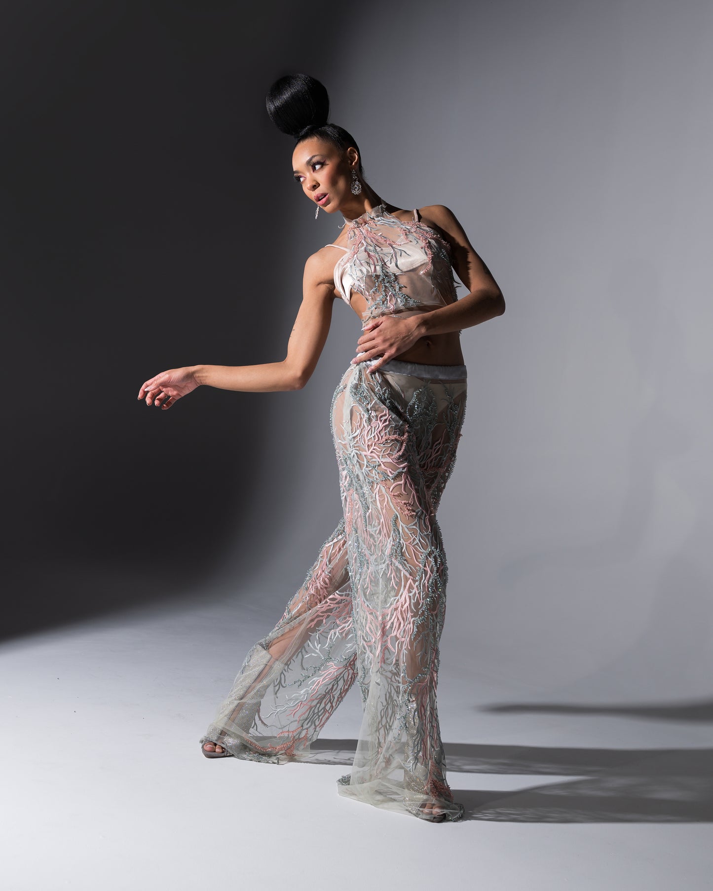 Model wearing a sheer, patterned outfit against a gray background