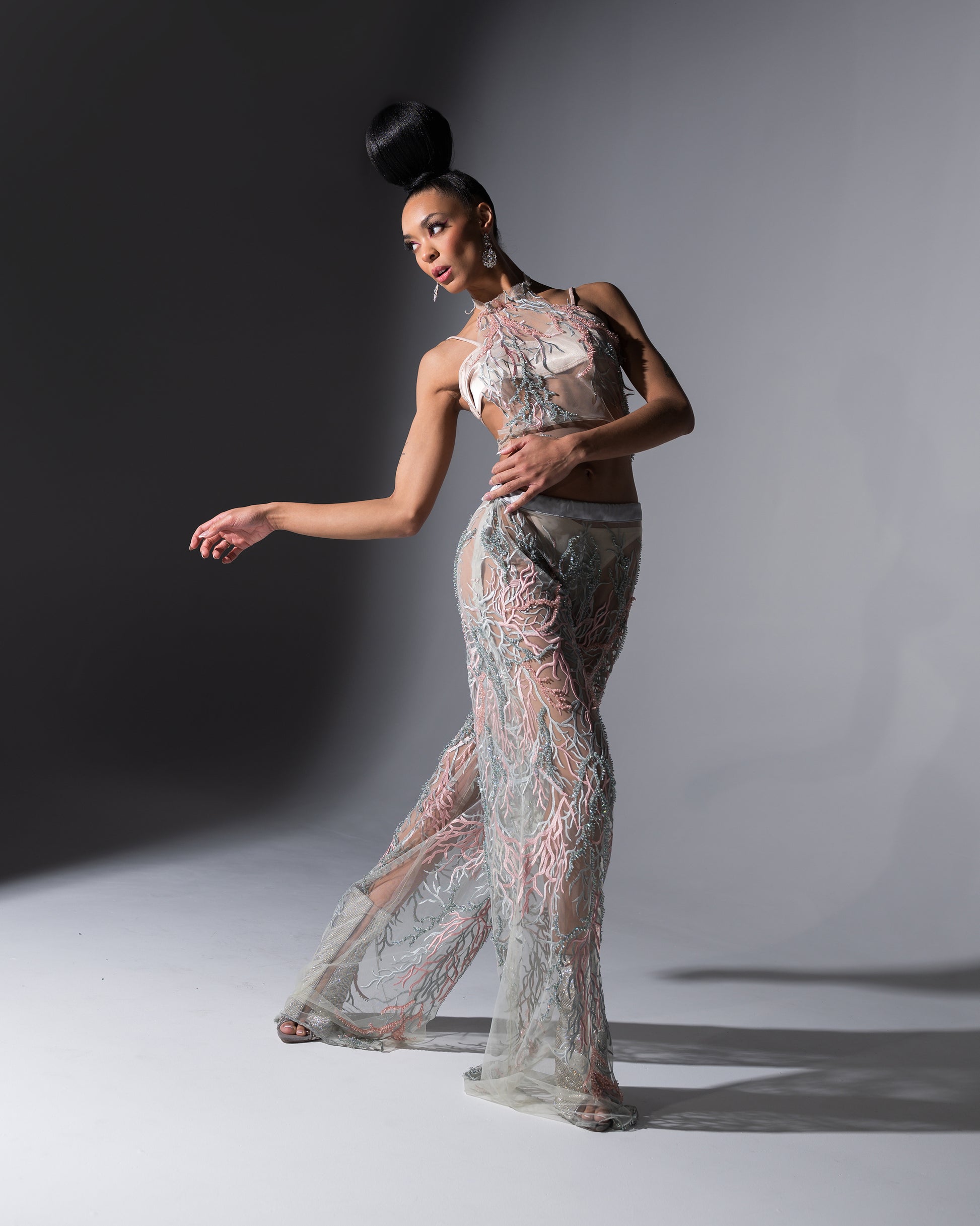 Model wearing a sheer, patterned outfit against a gray background